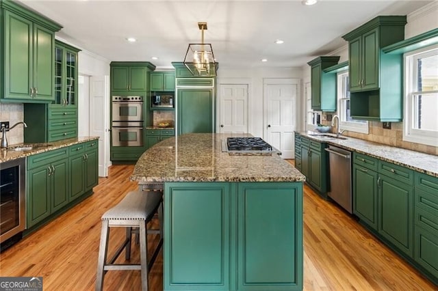 kitchen featuring a breakfast bar, a sink, decorative backsplash, wine cooler, and built in appliances