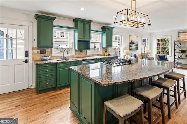 kitchen featuring decorative backsplash, green cabinets, light wood-style floors, and a sink