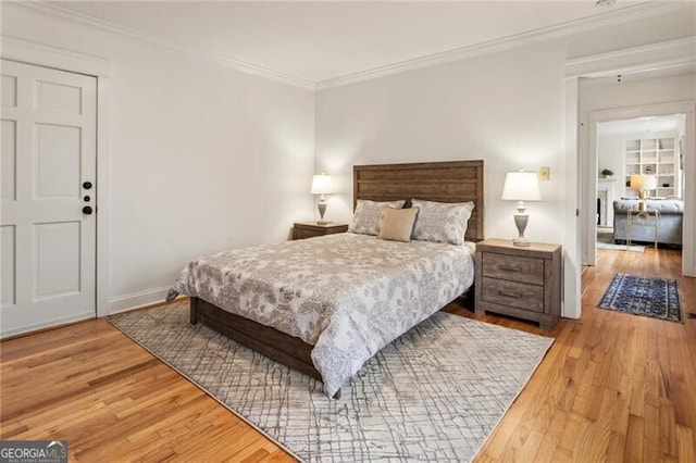 bedroom featuring baseboards, wood finished floors, and crown molding