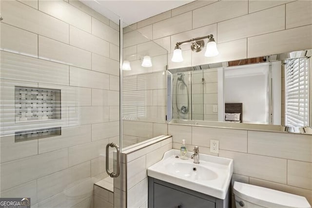 bathroom with vanity, tile walls, toilet, and a stall shower