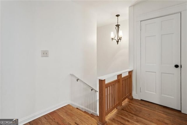 staircase with baseboards, an inviting chandelier, and wood finished floors