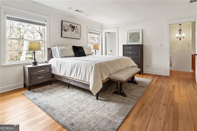 bedroom featuring visible vents, a notable chandelier, ornamental molding, light wood-style floors, and baseboards