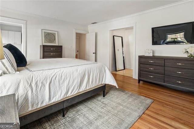 bedroom featuring visible vents, crown molding, and wood finished floors