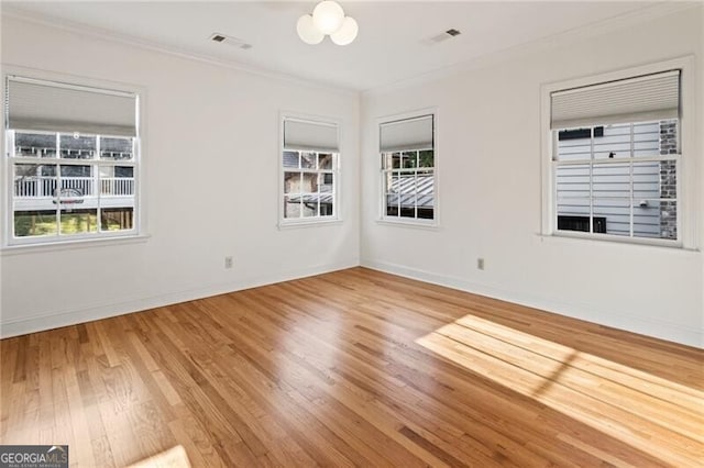 spare room with visible vents, crown molding, baseboards, and wood finished floors