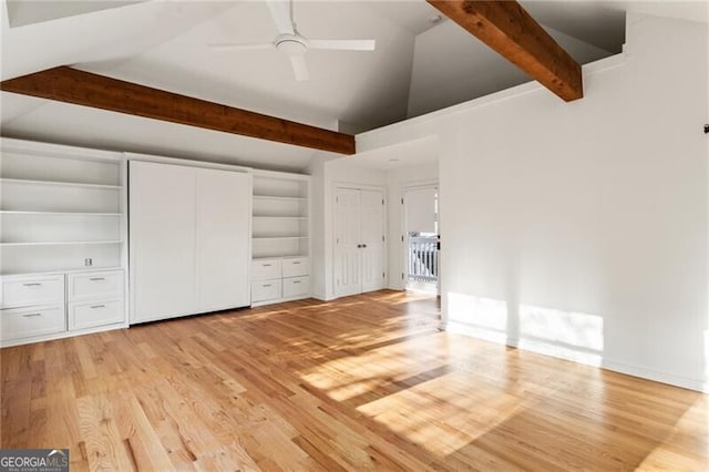 unfurnished bedroom with a ceiling fan, baseboards, vaulted ceiling with beams, light wood-style floors, and multiple closets