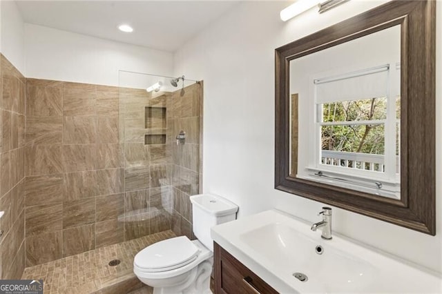 bathroom with vanity, toilet, and a tile shower