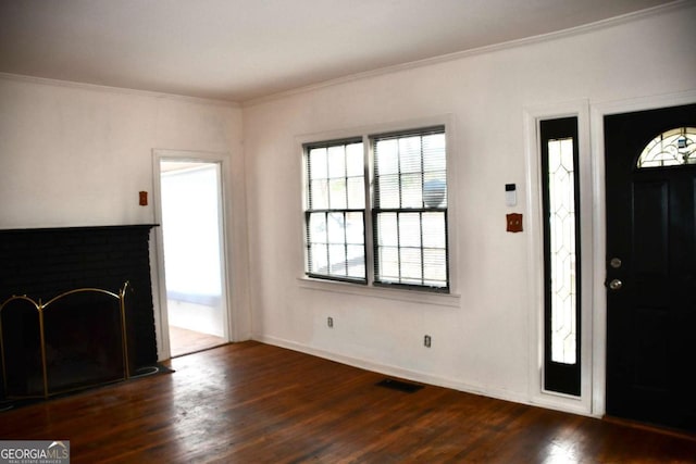 entryway with dark wood finished floors, visible vents, crown molding, and baseboards