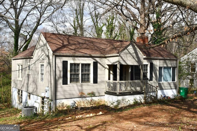 view of front of house featuring central air condition unit, a porch, and a chimney