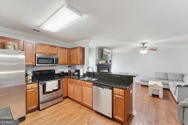 kitchen featuring visible vents, a peninsula, a sink, appliances with stainless steel finishes, and open floor plan