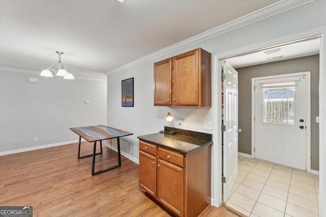 kitchen featuring crown molding, brown cabinetry, light wood-style floors, and a chandelier