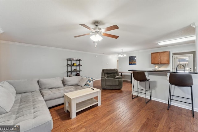 living room with ceiling fan with notable chandelier, ornamental molding, and hardwood / wood-style flooring