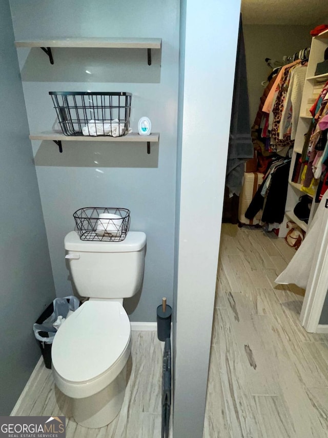 bathroom featuring toilet, baseboards, and wood tiled floor