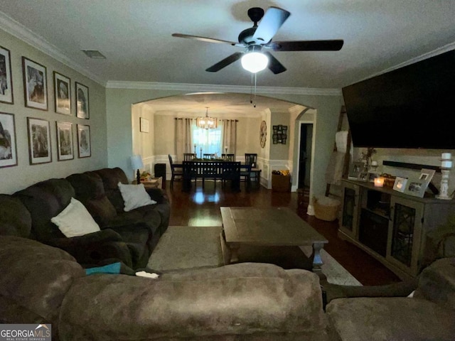 living room with arched walkways, wood finished floors, ornamental molding, and ceiling fan with notable chandelier