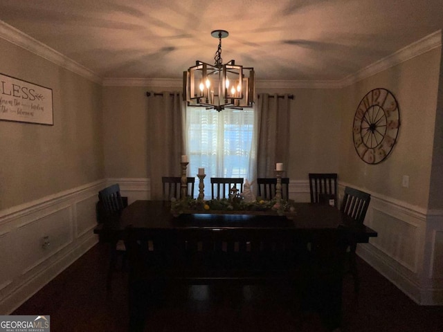 dining space featuring crown molding, a wainscoted wall, and a chandelier