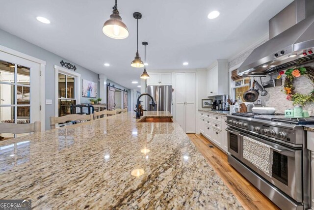 4770 Hilltop Dr NW, Acworth, GA 30101 - kitchen featuring appliances with stainless steel finishes, wall chimney exhaust hood, white cabinetry, light wood finished floors, and recessed lighting