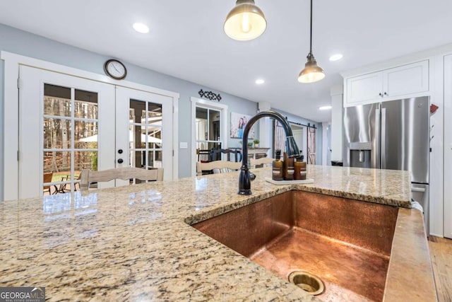 4770 Hilltop Dr NW, Acworth, GA 30101 - kitchen featuring stainless steel fridge, light stone counters, pendant lighting, french doors, and white cabinetry