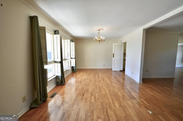 spare room featuring a notable chandelier, light wood-style flooring, and baseboards