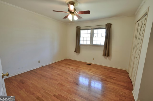 unfurnished bedroom with a ceiling fan, baseboards, light wood-style floors, a closet, and crown molding