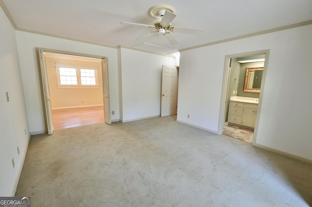 unfurnished bedroom with connected bathroom, ceiling fan, baseboards, light colored carpet, and ornamental molding