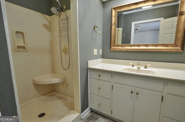 full bath featuring vanity, a textured wall, and a stall shower