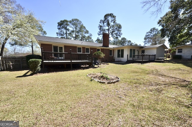 back of house featuring brick siding, fence, a wooden deck, a chimney, and a yard