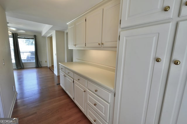 kitchen with dark wood finished floors, white cabinets, light countertops, and baseboards