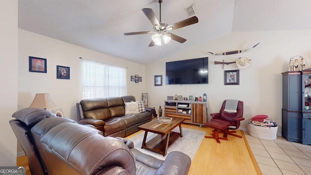 living area with a ceiling fan, visible vents, vaulted ceiling, a textured ceiling, and light wood-type flooring