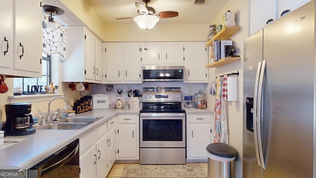 kitchen featuring backsplash, light tile patterned floors, appliances with stainless steel finishes, a ceiling fan, and a sink