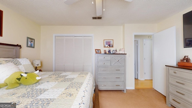 bedroom featuring visible vents, a textured ceiling, a closet, light colored carpet, and ceiling fan