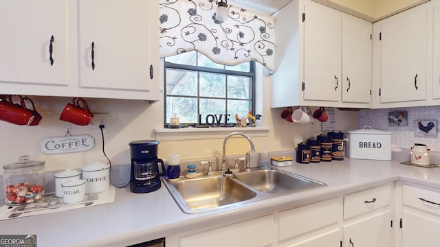 kitchen featuring white cabinets, light countertops, and a sink