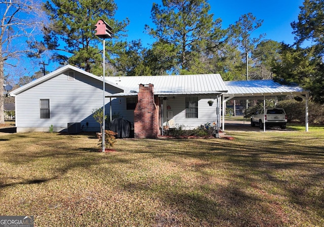 rear view of property with a carport, central AC, metal roof, and a yard