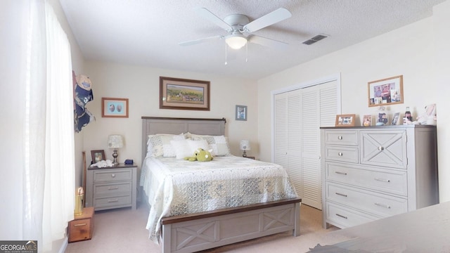 bedroom featuring visible vents, light carpet, a closet, a textured ceiling, and a ceiling fan