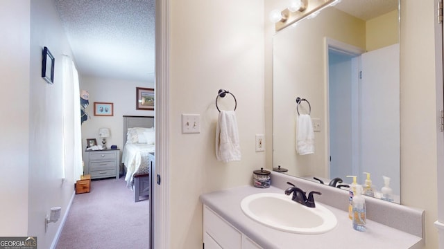 bathroom featuring a textured ceiling, ensuite bath, and vanity