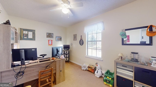 office area with a textured ceiling, light colored carpet, baseboards, and ceiling fan