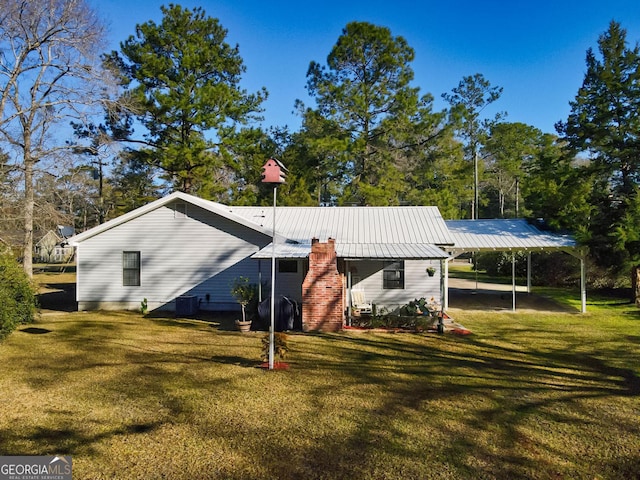 rear view of house featuring a carport, a lawn, and metal roof