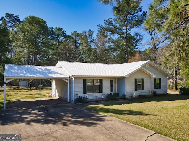 ranch-style house with an attached carport, driveway, metal roof, and a front lawn