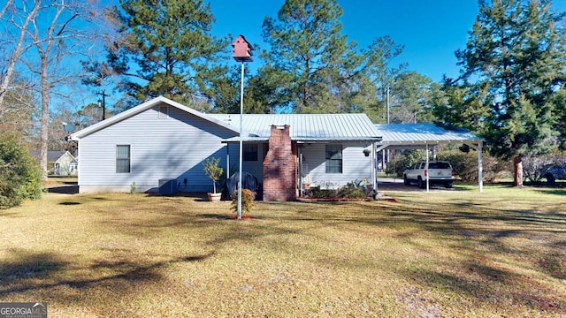 back of property with a carport, a lawn, and metal roof