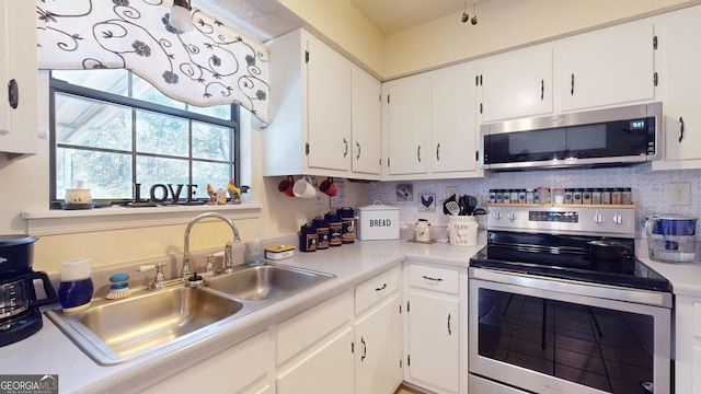 kitchen featuring appliances with stainless steel finishes, white cabinetry, light countertops, and a sink