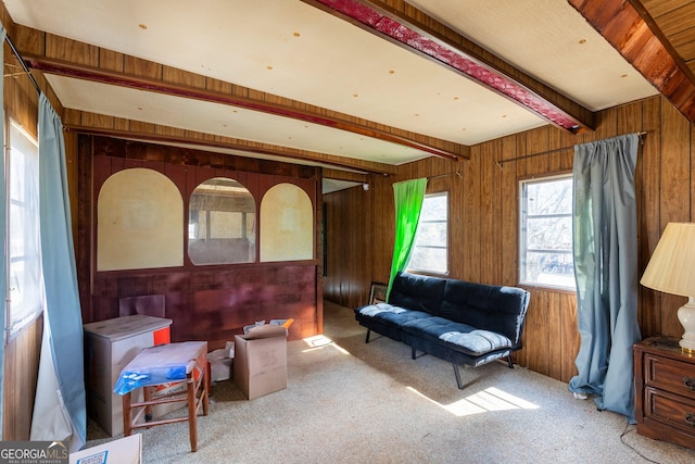 living area featuring beamed ceiling, carpet flooring, and wood walls