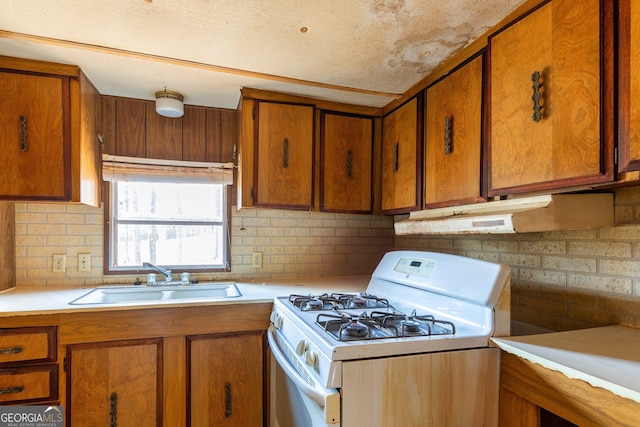 kitchen featuring a sink, white gas stove, brown cabinetry, and light countertops