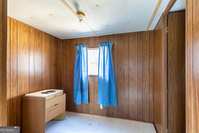 unfurnished bedroom with concrete floors and wood walls