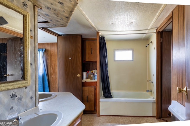 bathroom with tile patterned flooring, wooden walls, shower / bath combo with shower curtain, vanity, and a textured ceiling