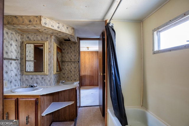 bathroom featuring double vanity, shower / bathtub combination with curtain, and a sink