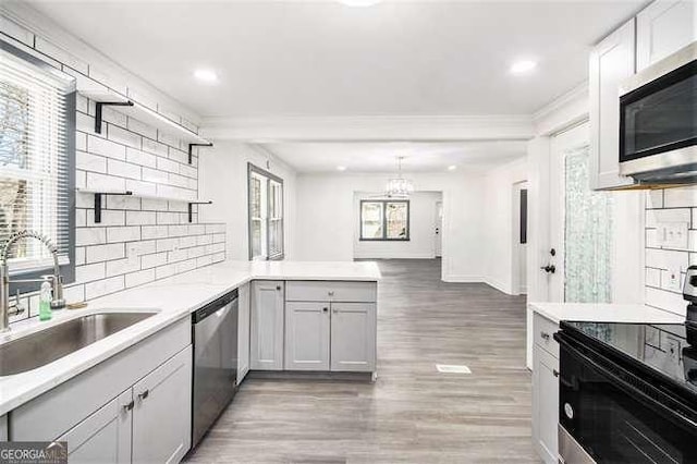 kitchen with open shelves, a sink, stainless steel appliances, a peninsula, and light countertops