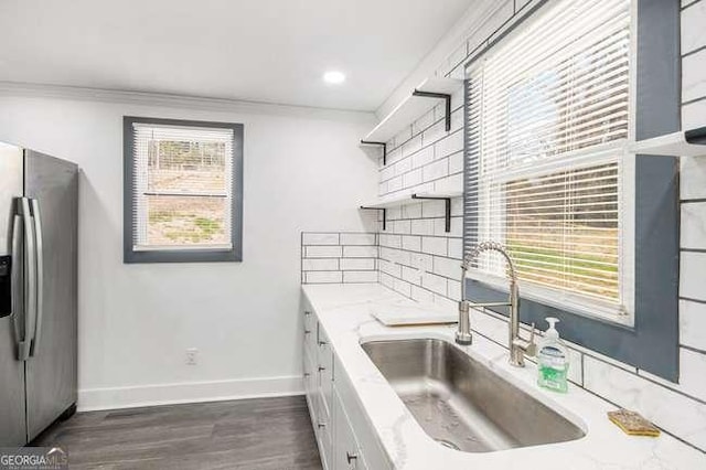 kitchen with baseboards, open shelves, a sink, decorative backsplash, and stainless steel fridge