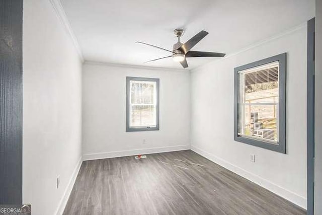 empty room featuring dark wood-style floors, baseboards, ornamental molding, and a ceiling fan