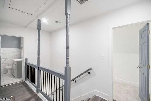 stairway with visible vents, attic access, and wood finished floors