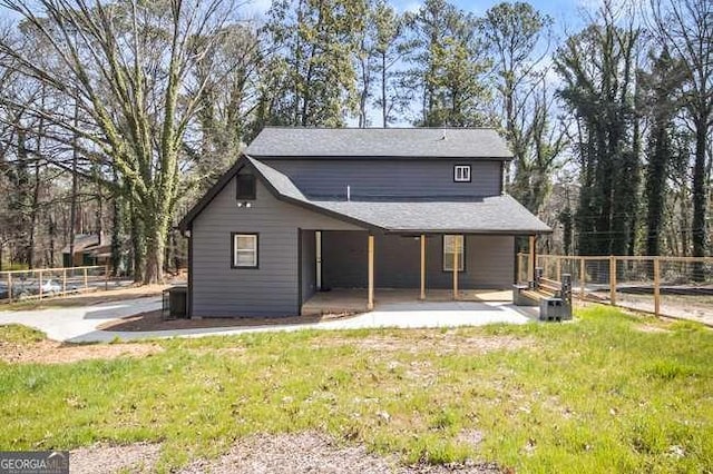 rear view of house with a lawn and fence