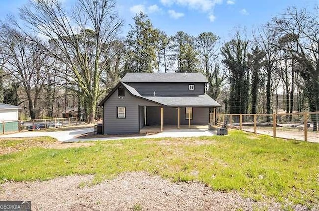 rear view of house featuring fence and a lawn