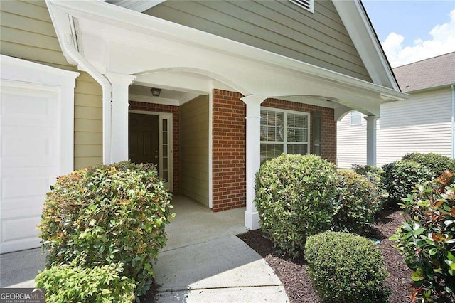 property entrance featuring a garage, covered porch, and brick siding